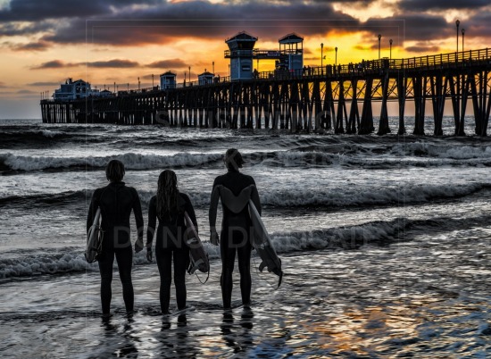 Surfers look on at sunset