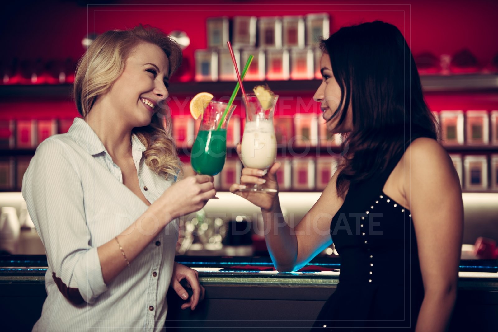 Two beautiful women drinking cocktail in a night club and having Photo ...